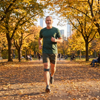 Homme qui court dans un parc en automne avec la sangle rotulienne